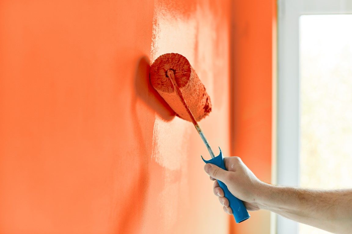 Close-up of a roller loaded with orange paint