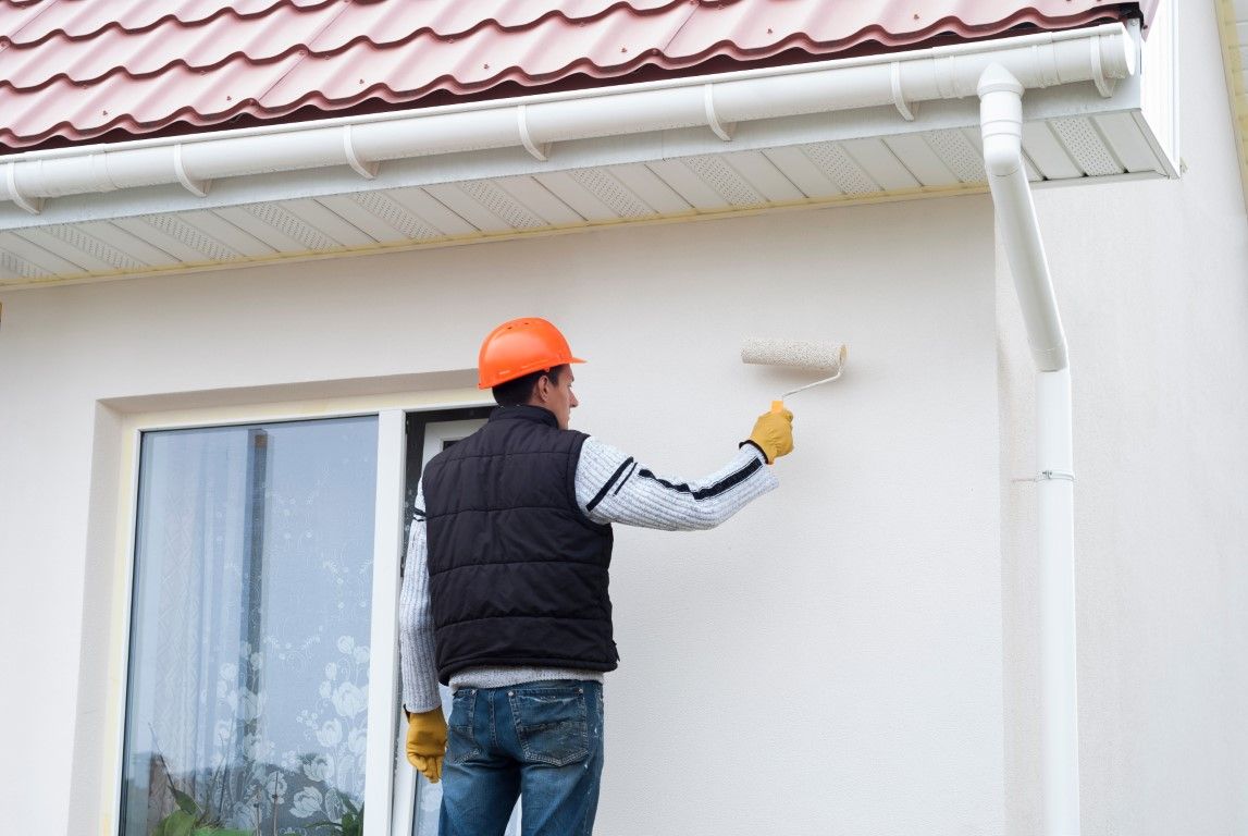 Painter working on exterior fascia and gutter trim