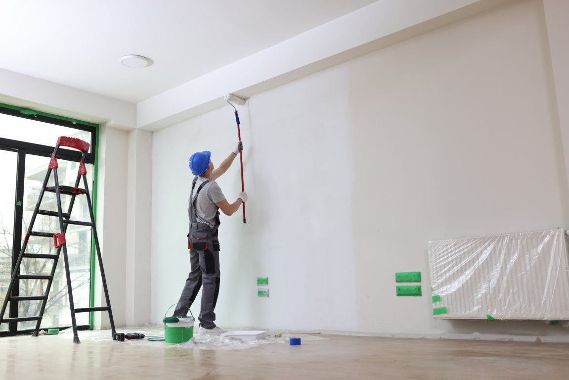 Painter prepping to roll a wall in a large empty room